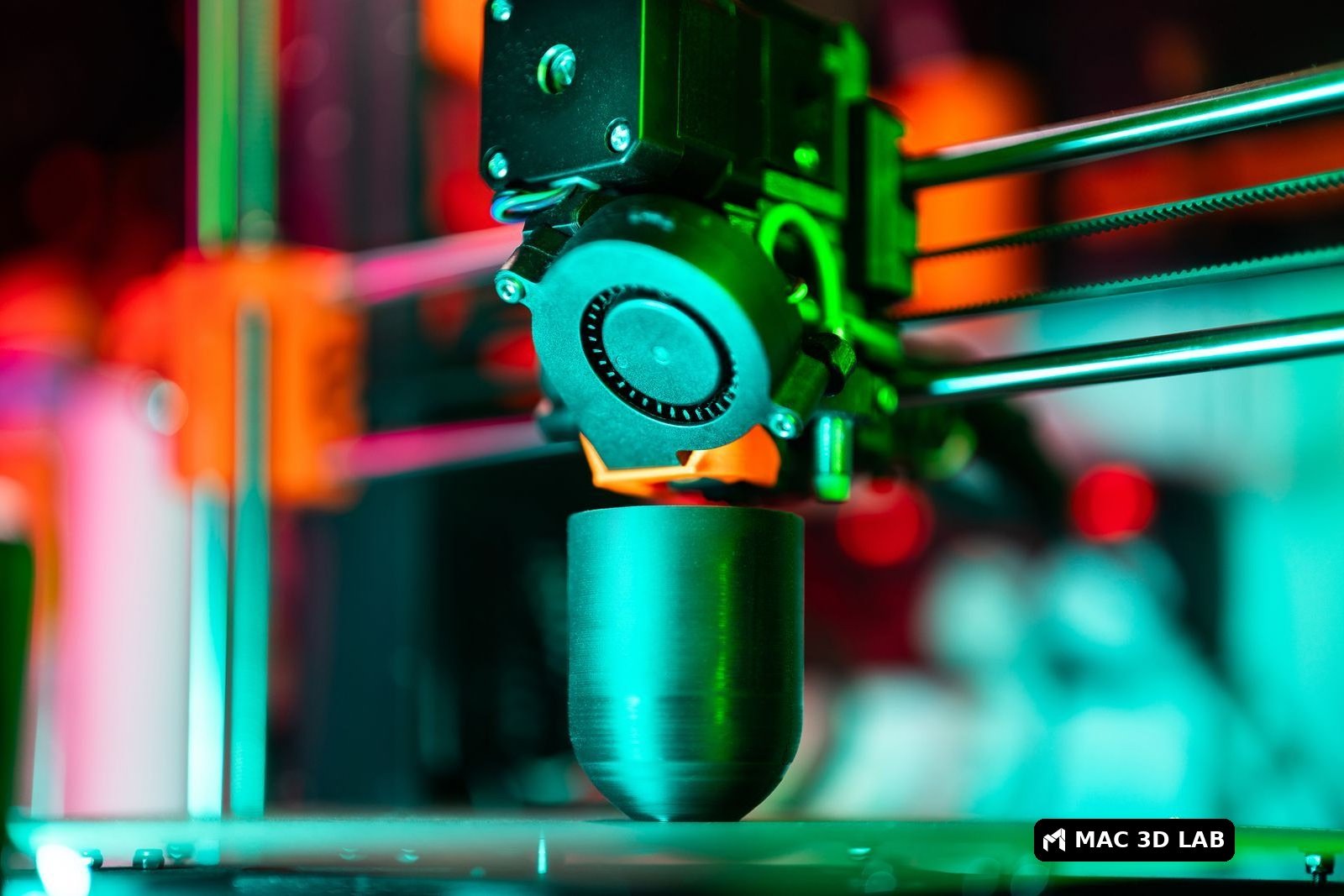 Impresora 3D imprimiendo una pieza con luz de neón